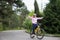Beautiful smiling teenage girl in a sports uniform and a bicycle helmet, arms outstretched, rides a yellow bicycle