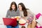 Beautiful smiling teenage girls watching movies on notebook