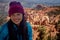 Beautiful smiling woman at Bryce Canyon in winter with blue coat and purple knit hat