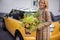 Beautiful smiling woman in coat stands with flower arrangement in her hand.