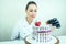 Beautiful and smiling woman confectioner in black gloves and white work uniform adorns the cake in the kitchen