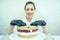 A beautiful and smiling woman confectioner in black gloves and a white working uniform bakes a cake in the kitchen