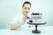 Beautiful and smiling woman confectioner in white work uniform adorns the cake in the kitchen. confectioner, cake
