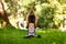 Beautiful smiling woman in morning park doing yoga and outdoor gymnastics. Green grass and rays of sun