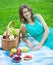 Beautiful smiling woman with picnic basket and fruits in summer