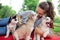 A beautiful smiling woman with a ponytail and wearing a striped shirt is cuddling with three sweet husky puppies while