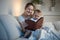 Beautiful smiling woman reading big old book to her baby boy before going to sleep