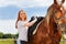 Beautiful smiling woman saddling a horse