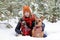 Beautiful smiling woman is sitting on a snow with her two dogs wrapped in red checkered plaid and two cup of hot tea.