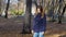 A beautiful smiling woman is standing in the autumn Park. 4k 60fps. Girl in a coat walking in the autumn city Park slow