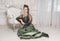 Beautiful smiling woman wearing green medieval vintage Victorian Style dress sitting on the floor near armchair