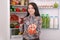 Beautiful smiling young girl holds a glass of pomegranate juice and garnet