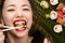 Beautiful smiling young Korean girl eating sushi rolls