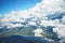 Beautiful snow-white clouds and a view of the green lands from the window of the airplane and part of the wing