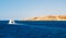 Beautiful snow-white yacht sails in the sea, into the distance. Rock in the background