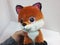 Beautiful soft toy with big eyes - an orange fox on a white background in the hands of women. present