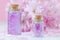 Beautiful spa composition, aroma oil, fresh sakura on pink background, selective focus