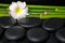 beautiful spa concept of zen basalt stones, white flower frangipani and natural bamboo with dew, closeup