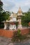 A beautiful spiritual house with dragons, figurines and incense bowls is standing in front of a residential building in Thailand