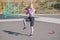 Beautiful and sportive blonde girl doing jumps on the street sports ground.