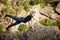 Beautiful sportive blonde girl stretching on rock in canyon.