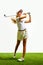 Beautiful, sportive, young blonde girl in white shorts and t-shirt playing golf on grass, teeing off isolated over white