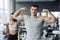 Beautiful sports couple is showing their muscles while standing in gym