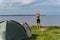 A beautiful sports girl stretches near a tent in nature, near the sea on the cliff of Paldiski in summer