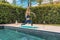 Beautiful sports woman practicing yoga near the swimming pool. Fitness, sport, exercising, making yoga pose outside