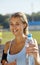 Beautiful sportsgirl in a stadium. Woman with bootle of water.