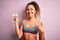 Beautiful sportswoman with curly hair doing sport wearing sportswear holding diet reminder happy with big smile doing ok sign,