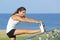 Beautiful sportswoman stretching with the sea in the background