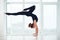Beautiful sporty fit yogi woman practices yoga handstand asana Bhuja Vrischikasana - Scorpion handstand pose at the yoga
