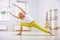 Beautiful sporty fit yogi woman practices yoga twist standing asana in the fitness room