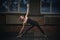Beautiful sporty fit yogini woman practices yoga asana Utthita Trikonasana - triangle pose in the dark hall