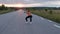 Beautiful, sporty girl doing squats on the road among nature at sunset