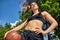 Beautiful, sporty latin girl with a basketball under the ring on a street basketball court. Sport motivation, healthy