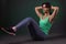 Beautiful sporty woman, fitness woman doing exercise on a dark background with green backlight