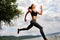 A beautiful sporty woman runing on the shore of a lake in sports