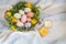 Beautiful spring bouquet in a wooden basket where Easter eggs painted with watercolors lie. There are burning candles nearby