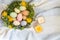 Beautiful spring bouquet in a wooden basket where Easter eggs painted with watercolors lie. There are burning candles nearby.