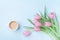 Beautiful spring breakfast on Mothers or Womans day. Bouquet of pink tulips and coffee cup on blue pastel table top view. Flat lay