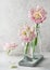Beautiful spring floristic arrangement with pastel white and rosa filled tulip flowers in glass bottle on vintage tray.