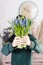 Beautiful spring flower bouquet. Delicate female hands holding a holds blue muscari flowers. Pink chest of drawers in
