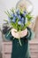 Beautiful spring flower bouquet. Delicate female hands holding a holds blue muscari flowers. Pink chest of drawers in