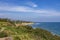 a beautiful spring landscape at Point Dume beach with blue ocean water, lush green trees and plants, homes along the cliffs, waves