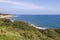 a beautiful spring landscape at Point Dume beach with blue ocean water, lush green trees and plants, homes along the cliffs, waves