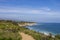 a beautiful spring landscape at Point Dume beach with blue ocean water, lush green trees and plants, homes along the cliffs, waves