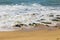 a beautiful spring landscape at Sandy Beach with blue ocean water, silky brown sand, rocks covered in green algae