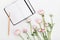 Beautiful spring Ranunculus flowers and empty notebook on white table from above. Mockup. Pastel color. Clean space for text.